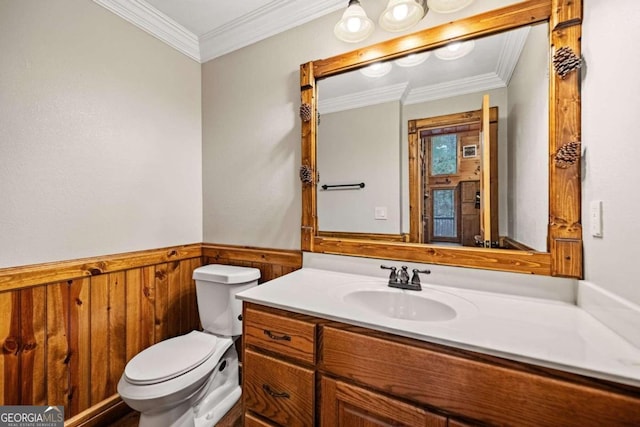 bathroom with crown molding, vanity, wooden walls, and toilet