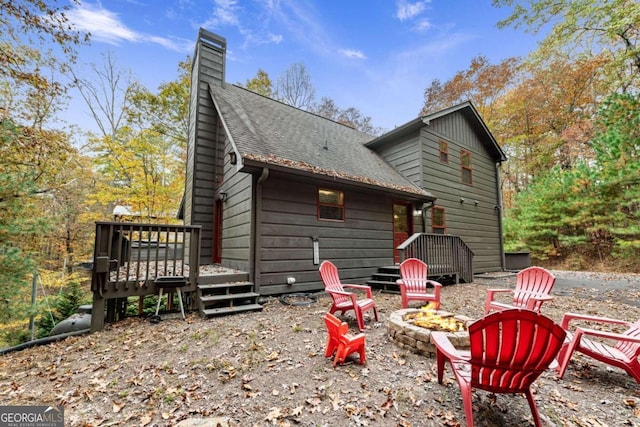 back of property with a fire pit and a deck