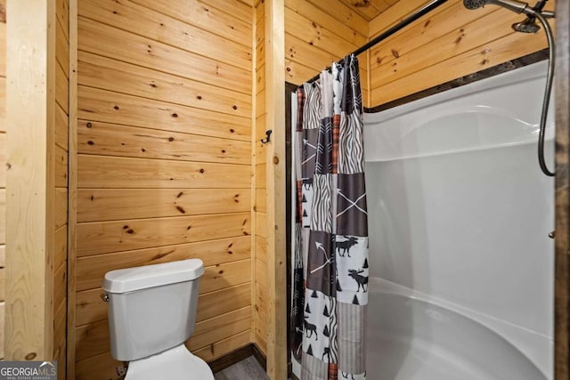 bathroom featuring wooden walls and toilet