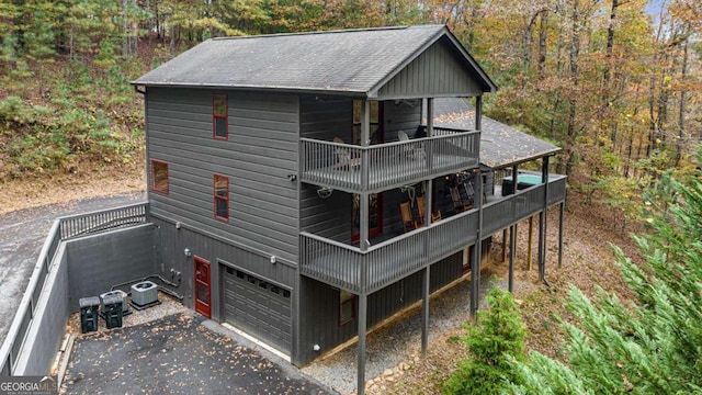 back of house featuring a garage, a balcony, and central AC unit