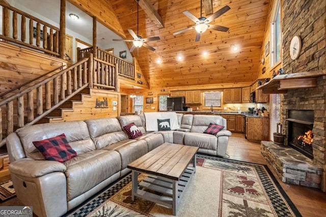 living room featuring a fireplace, wood walls, beamed ceiling, wooden ceiling, and light wood-type flooring