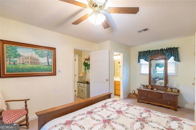 bedroom featuring connected bathroom, a textured ceiling, light carpet, and ceiling fan