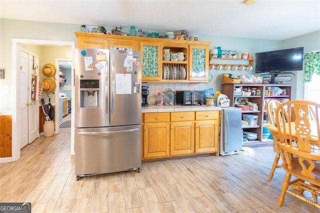 kitchen featuring stainless steel refrigerator with ice dispenser, light hardwood / wood-style flooring, and tile countertops