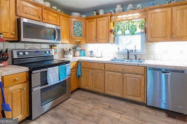 kitchen featuring tile counters, stainless steel appliances, sink, and tasteful backsplash