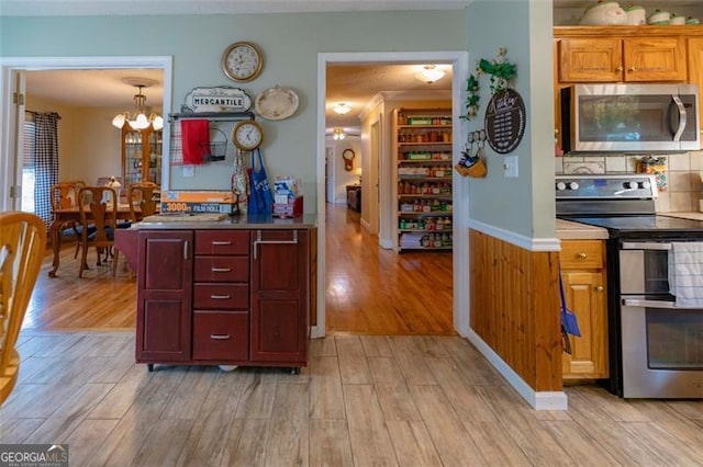 kitchen featuring stainless steel appliances, light hardwood / wood-style floors, backsplash, decorative light fixtures, and a notable chandelier