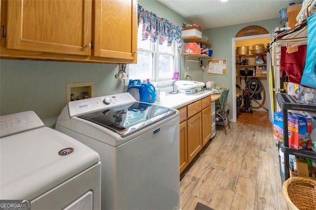 clothes washing area with light wood-type flooring, cabinets, and independent washer and dryer