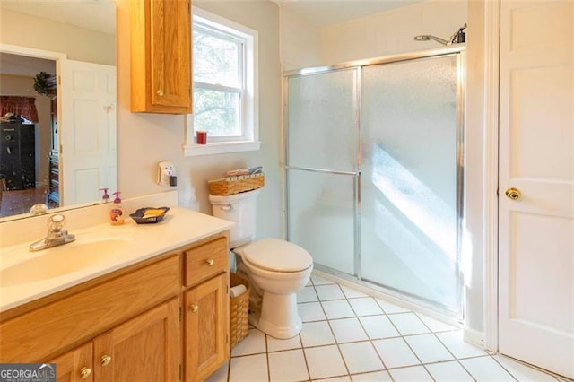 bathroom with vanity, tile patterned floors, toilet, and a shower with door