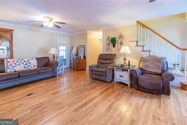 living room featuring a textured ceiling, light wood-type flooring, ceiling fan, and crown molding