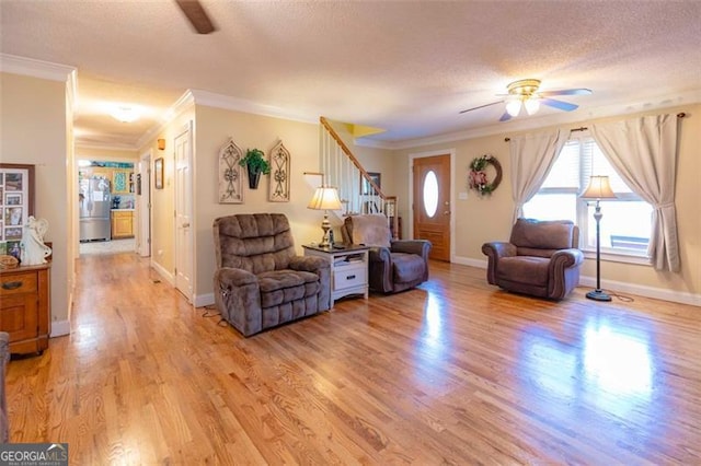 living room with ceiling fan, a textured ceiling, light hardwood / wood-style flooring, and ornamental molding