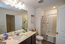 full bathroom with vanity, a notable chandelier, shower / bath combo with shower curtain, and toilet