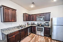 kitchen featuring dark brown cabinets, sink, appliances with stainless steel finishes, light stone counters, and light hardwood / wood-style floors