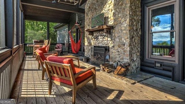 wooden deck with an outdoor stone fireplace