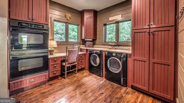 kitchen with light stone countertops, separate washer and dryer, built in desk, double oven, and hardwood / wood-style flooring