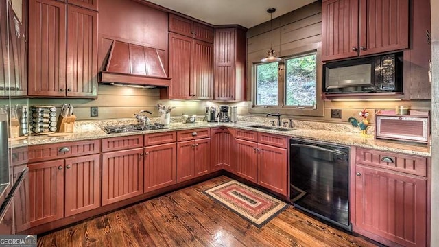 kitchen with black appliances, sink, decorative light fixtures, dark wood-type flooring, and premium range hood