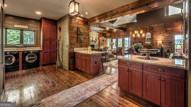 kitchen with dark hardwood / wood-style floors, a healthy amount of sunlight, light stone countertops, and washing machine and dryer