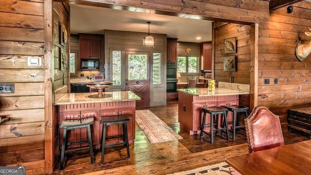 kitchen featuring black appliances, dark hardwood / wood-style flooring, a kitchen bar, and a kitchen island