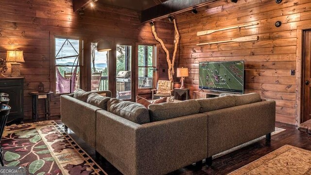 living room with wood walls, beamed ceiling, and dark hardwood / wood-style flooring