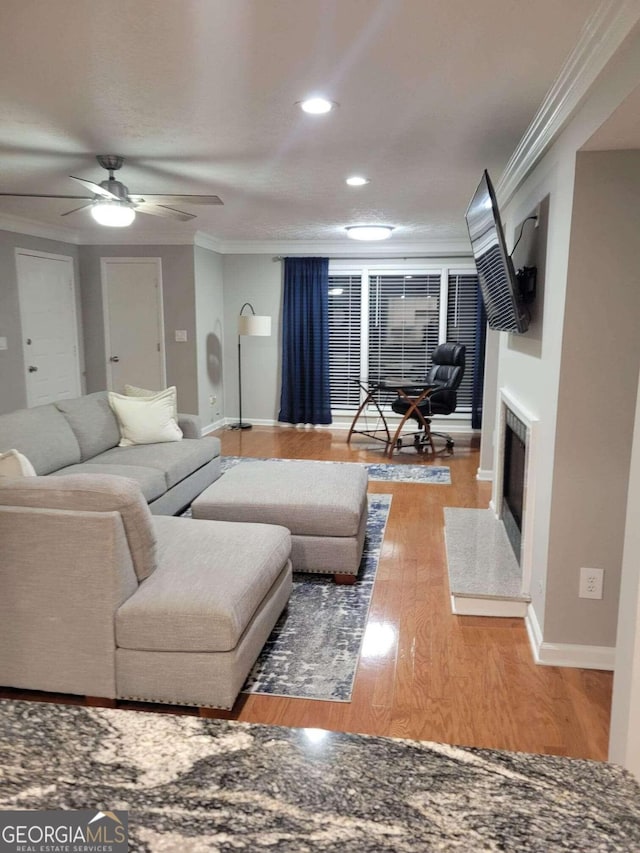 living room with ornamental molding, wood-type flooring, and ceiling fan