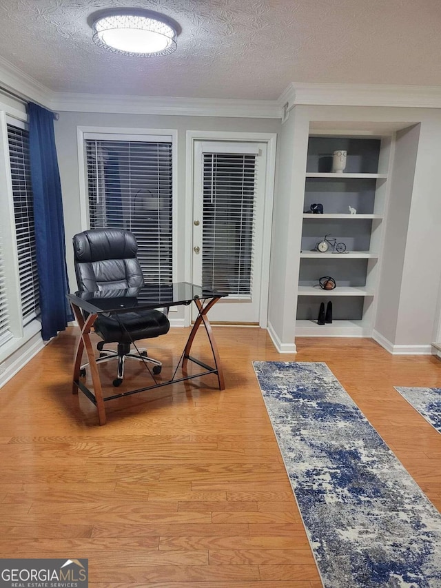 office space featuring ornamental molding, a textured ceiling, wood-type flooring, and built in features