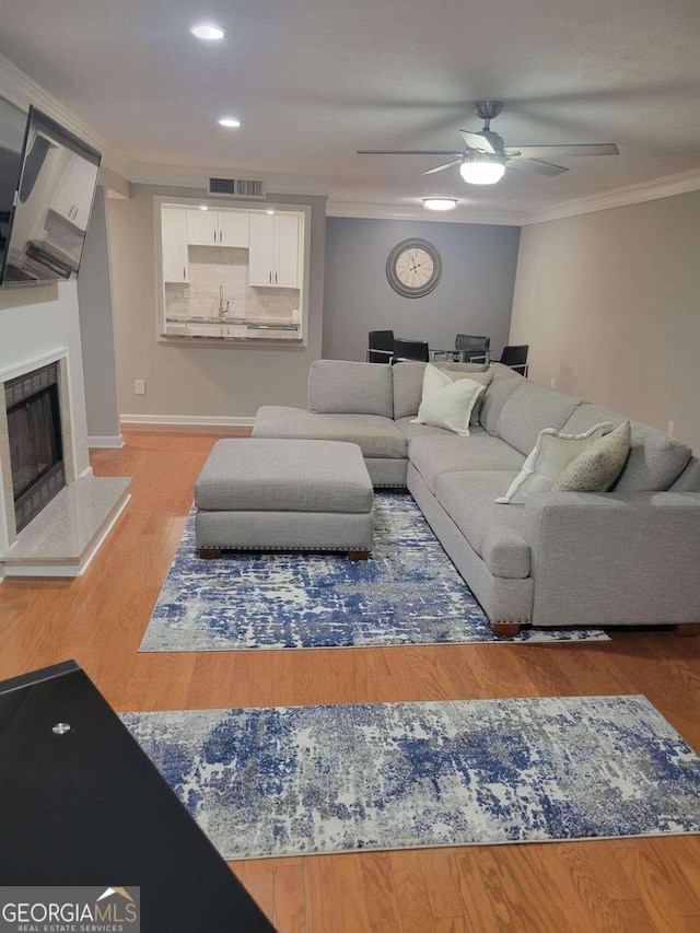 living room with crown molding, wood-type flooring, and ceiling fan