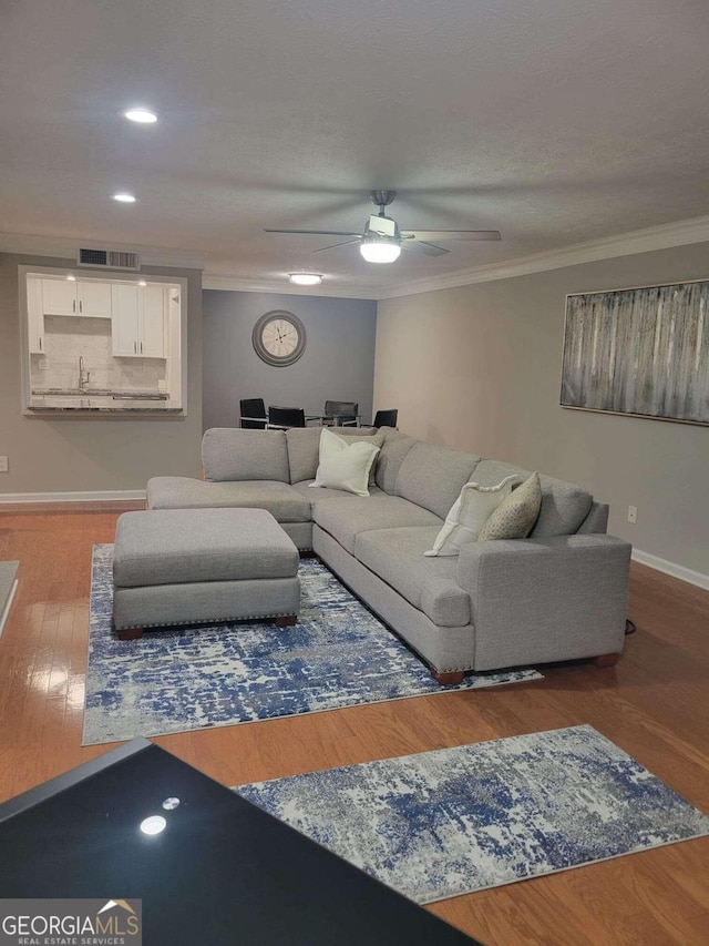 living room with ceiling fan, wood-type flooring, and ornamental molding