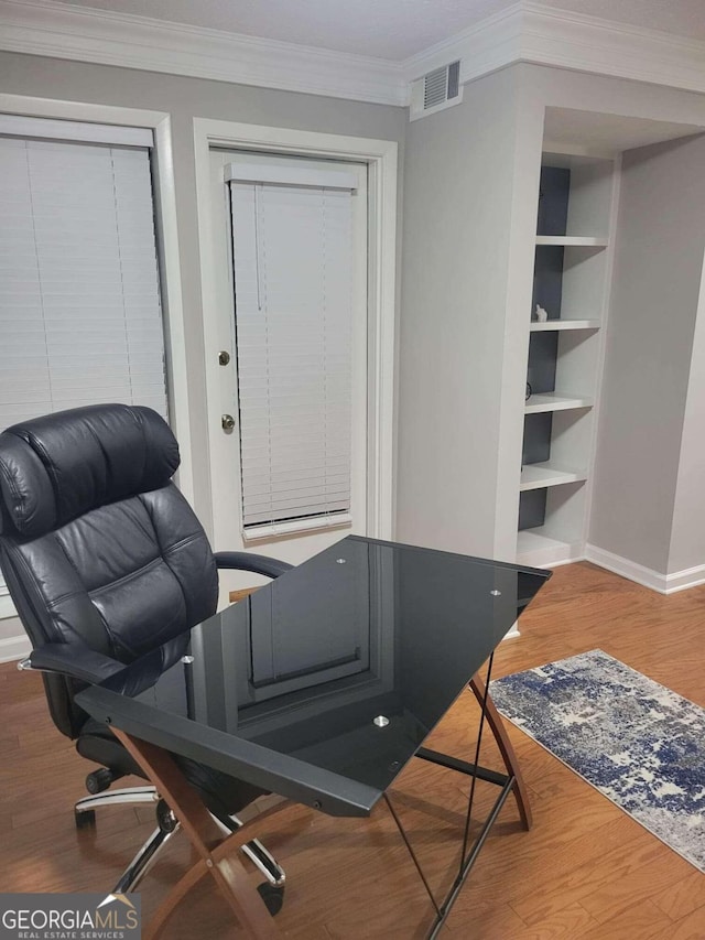 office space featuring crown molding, built in shelves, and hardwood / wood-style floors