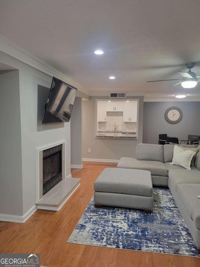 living room featuring hardwood / wood-style floors, crown molding, and ceiling fan