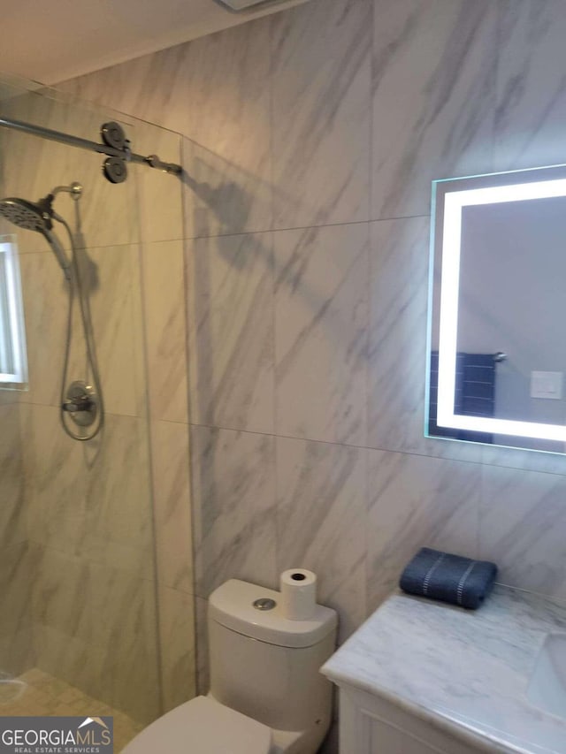 bathroom featuring vanity, toilet, tile walls, and tiled shower