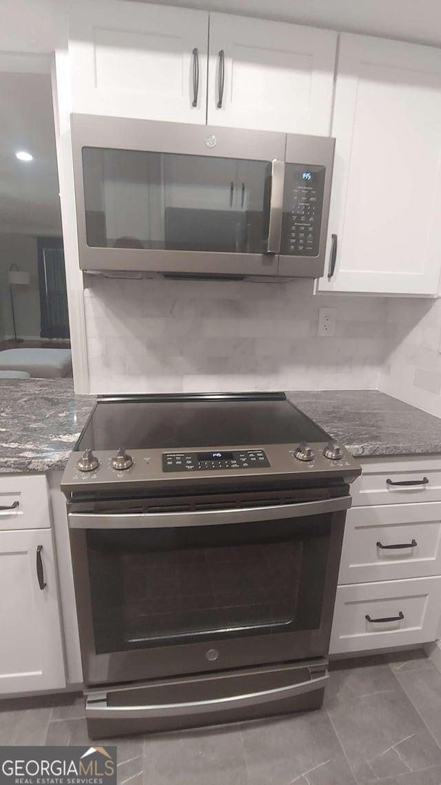 kitchen with white cabinetry, stainless steel appliances, and dark stone counters