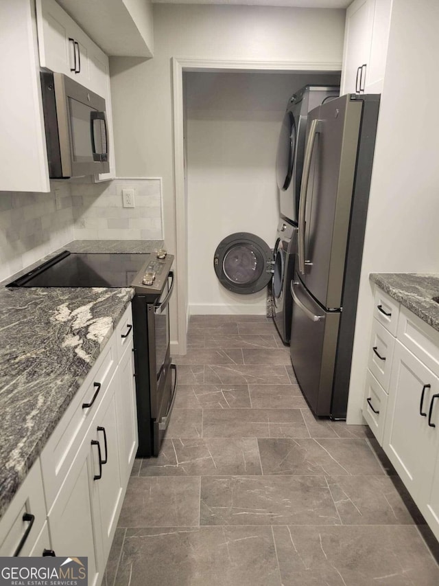 kitchen featuring backsplash, stacked washer / drying machine, appliances with stainless steel finishes, and white cabinetry