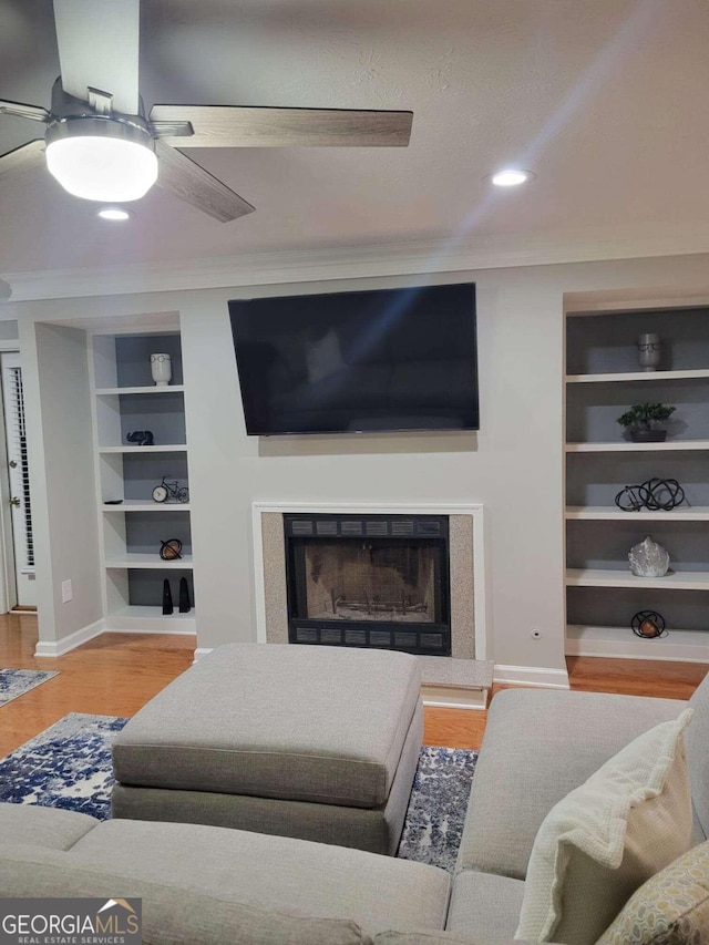 living room featuring ceiling fan, light hardwood / wood-style flooring, and built in shelves