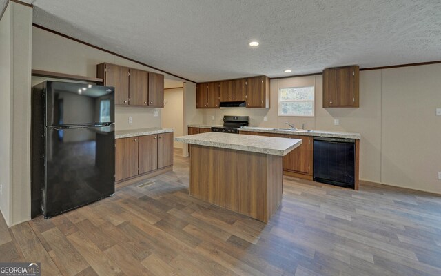 kitchen with a kitchen island, black appliances, a textured ceiling, and light wood-type flooring