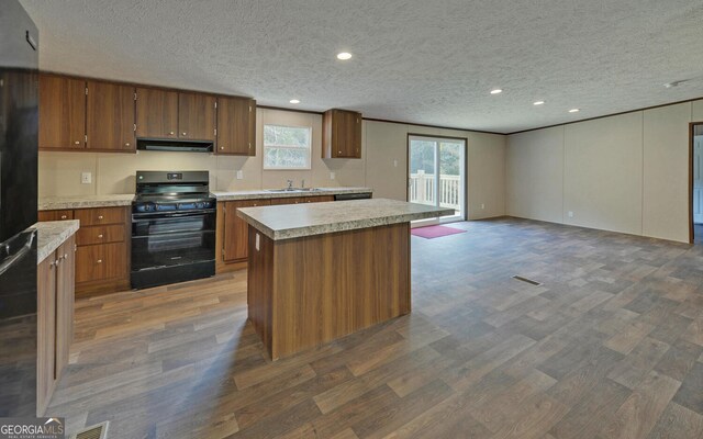 kitchen with dark hardwood / wood-style floors, black appliances, a textured ceiling, and a kitchen island