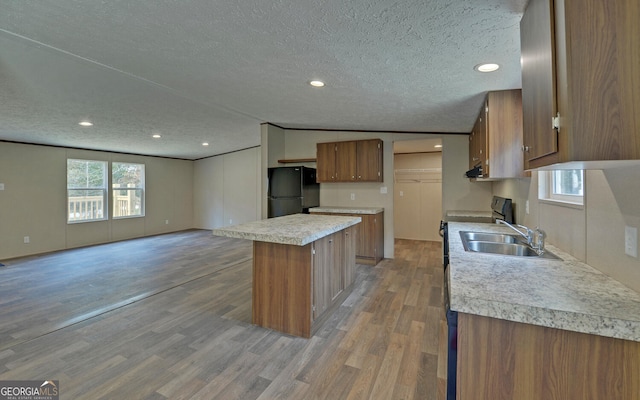 kitchen with a healthy amount of sunlight, a textured ceiling, a center island, and black refrigerator