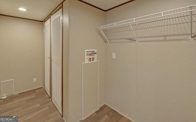 washroom with crown molding, wood-type flooring, and washer hookup