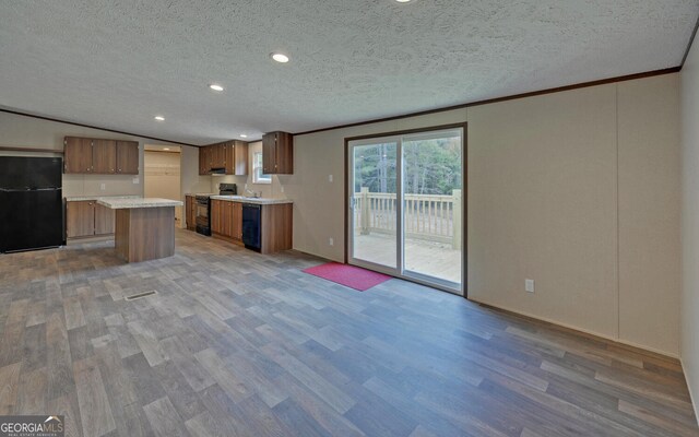 kitchen with sink, black appliances, a center island, a textured ceiling, and light hardwood / wood-style floors