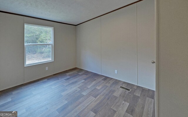 unfurnished room featuring crown molding, a textured ceiling, and light hardwood / wood-style flooring