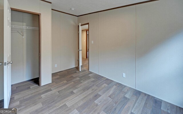 unfurnished bedroom featuring a closet, crown molding, and light hardwood / wood-style floors