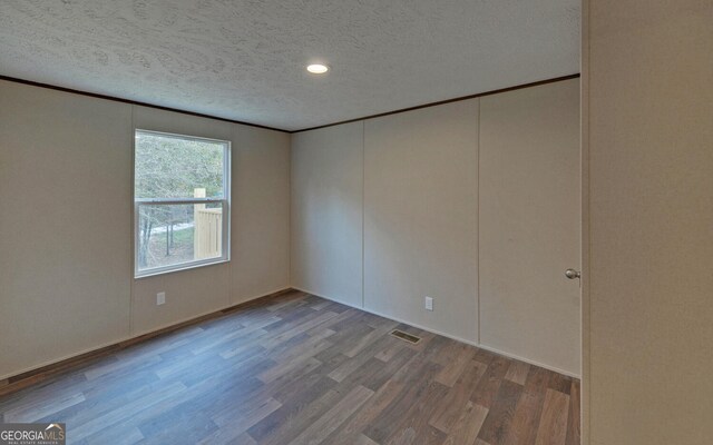 empty room with a textured ceiling and hardwood / wood-style flooring