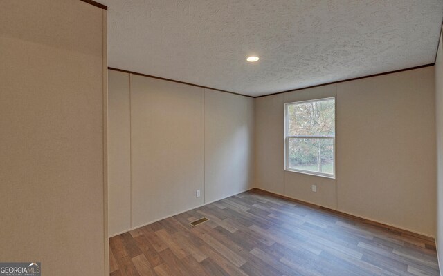 spare room with a textured ceiling and wood-type flooring