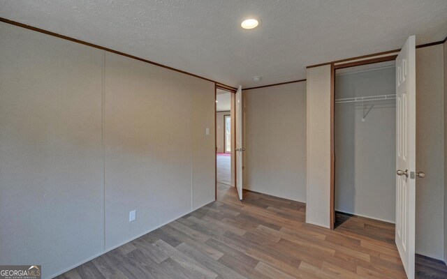 unfurnished bedroom with light hardwood / wood-style flooring and a textured ceiling