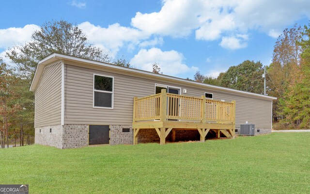 back of house featuring a deck, a lawn, and central AC