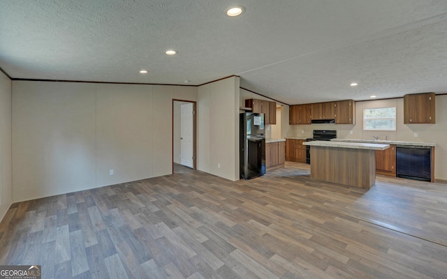 kitchen featuring light hardwood / wood-style flooring, ornamental molding, black appliances, a center island, and a textured ceiling