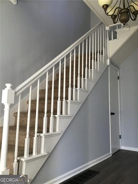 stairway with wood finished floors, baseboards, and a chandelier
