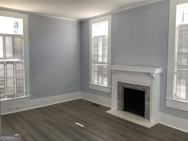 unfurnished living room with ornamental molding, wood finished floors, a brick fireplace, and baseboards