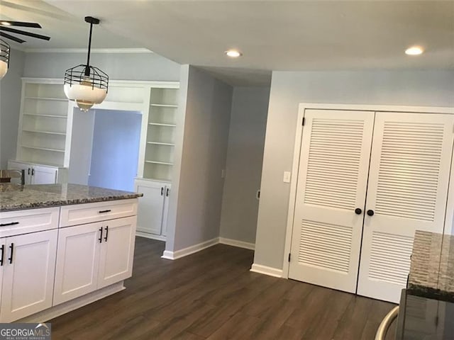 kitchen with baseboards, dark wood finished floors, white cabinetry, dark stone counters, and hanging light fixtures
