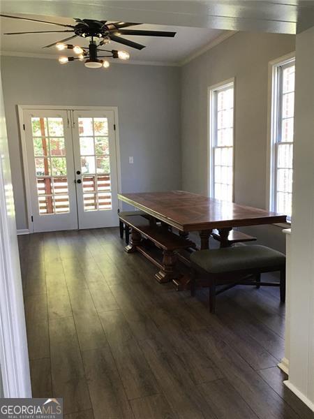 dining space with dark wood-type flooring, crown molding, french doors, and a wealth of natural light