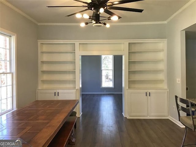 unfurnished dining area with healthy amount of natural light, ceiling fan, dark wood finished floors, crown molding, and baseboards