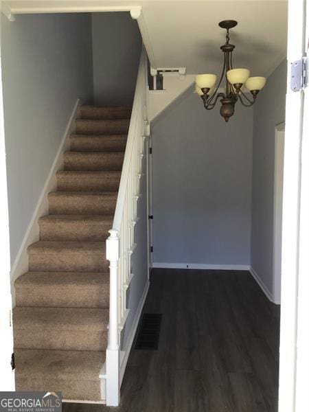 stairs with wood finished floors, a chandelier, and baseboards