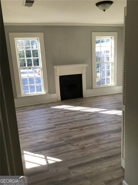 unfurnished living room with ornamental molding, plenty of natural light, a fireplace, dark wood-style flooring, and baseboards